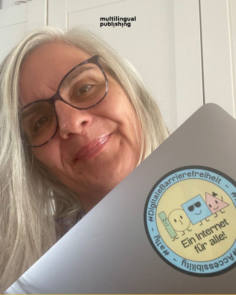 Yvonne Frank mit ihrem Laptop in der Hand. Ihr Laptop hat den digitalen Barrierefreiheit-Sticker darauf!