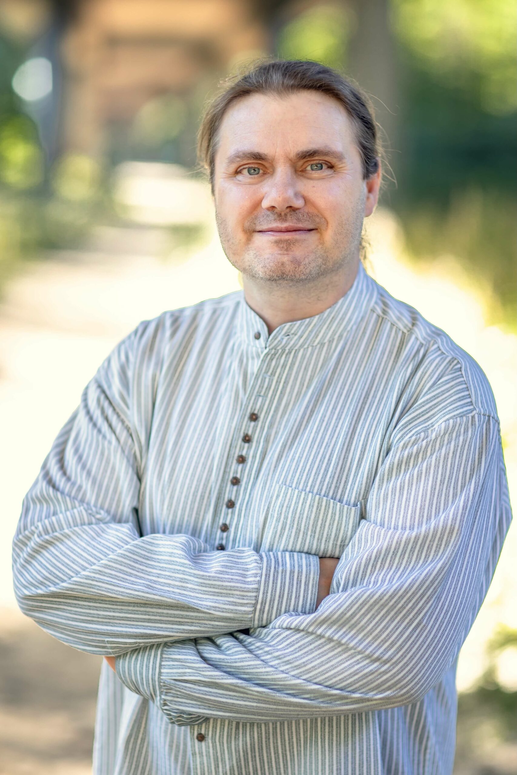 Der Barrierefreiheits-Tester Marc Haunschild hat lange braune Haare und grüne Augen. Er trägt ein weiß-grau gestreiftes Hemd.